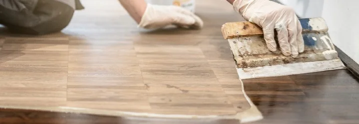 Person trägt Lack auf Holzboden auf